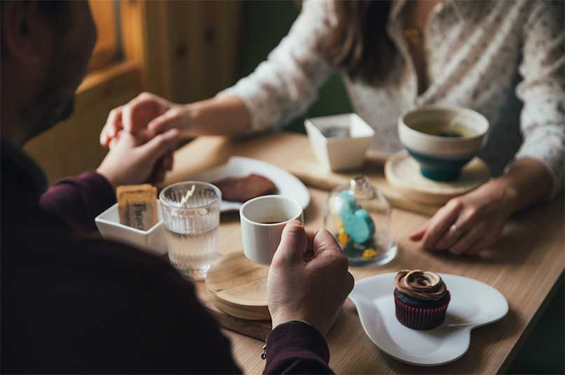 pareja se agarra las manos en una cita desayunando