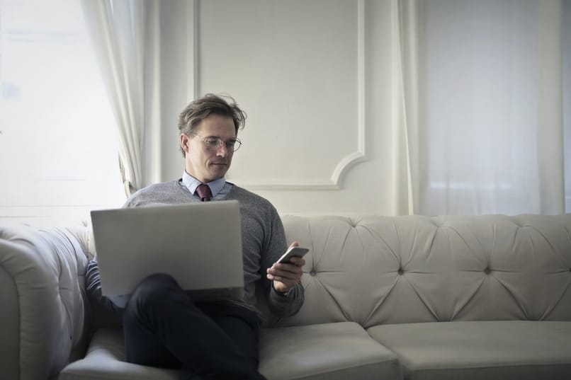 seated man using his computer and phone