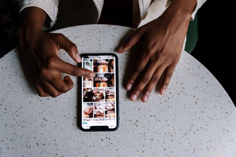 smartphone con instagram y manos sobre escritorio