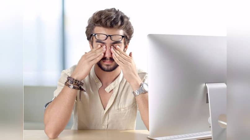 person covering their eyes in front of the computer