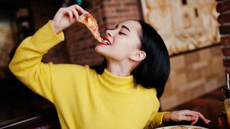 mujer restaurante comer rebanada pizza llevar a boca