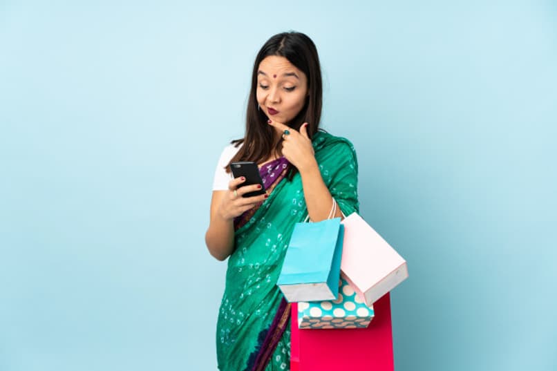 mujer sostiene unas bolsas y un telefono