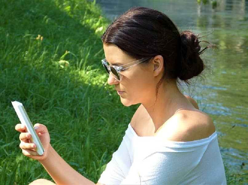mujer con lentes viendo su telefono al aire libre