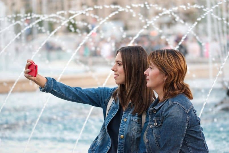 women taking selfie in front of fountain