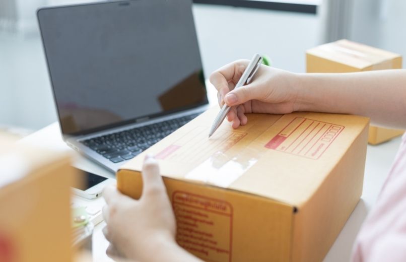person writing a shipping label on a package