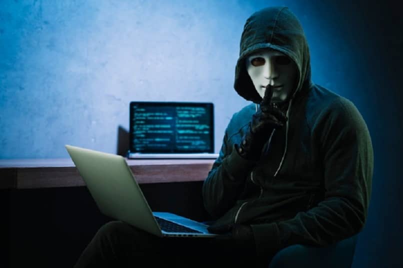 persona con una mascara blanca y laptop en la mano