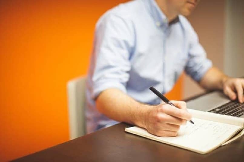 man writing in notebook in office