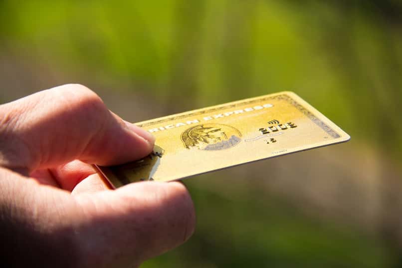 mano sostiene una tarjeta de credito american express